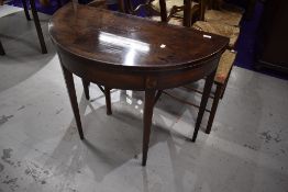 A 19th Century mahogany demi lune fold over tea table having inlaid detailing on tapered legs