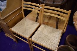 A pair of beech frame rail back kitchen chairs having rush seats