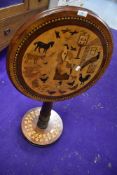 A Victorian tilt top tea table having naive farm yard and animal veneer top with bun foot ivy