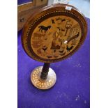 A Victorian tilt top tea table having naive farm yard and animal veneer top with bun foot ivy