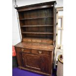 A 19th Century oak dresser of naive form, having utility style base on bun feet