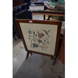 An early mahogany folding firescreen/tea trolley, having embroidered panel