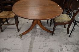 A 19th Century mahogany table having tilt top, turned column, triple splay legs and brass bad feet