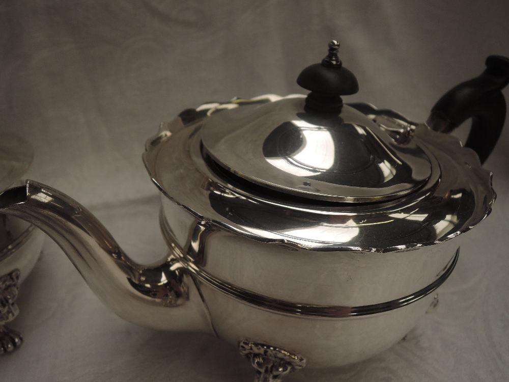 A 1920's silver four piece tea set of plain form having reided waists, lion mask paw feet and shaped - Image 2 of 4