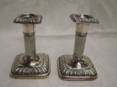 A pair of Edwardian silver candlesticks of squat Corinthian form having weighted bases, Birmingham