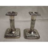 A pair of Edwardian silver candlesticks of squat Corinthian form having weighted bases, Birmingham