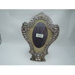 A Victorian silver photograph frame of cartouche form having a silver border with scroll, cherubic