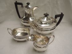 A silver four piece tea set of canted ovoid form having gadrooned rims, wooden handles and knops and