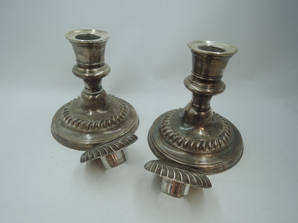 A pair of Edwardian silver candle sticks of squat form having gadrooned decoration, removable