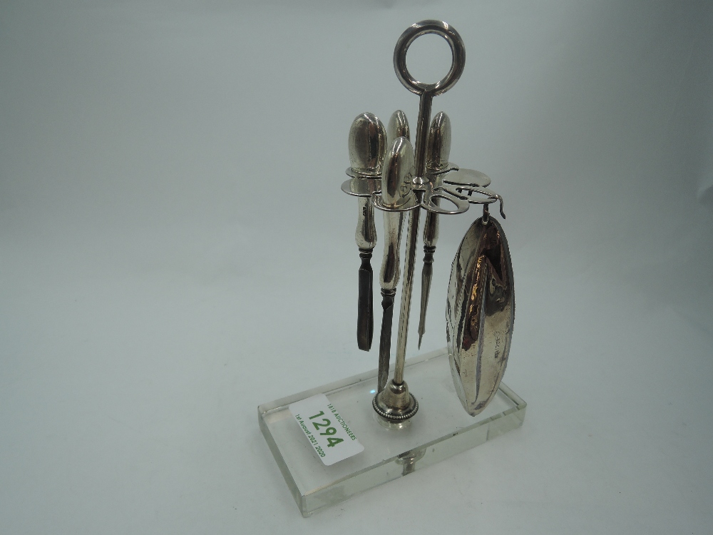 A white metal dressing table manicure stand having five HM silver handled manicure tools to white