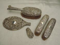 A selection of HM silver dressing table items including brushes with repousse cherubic decoration