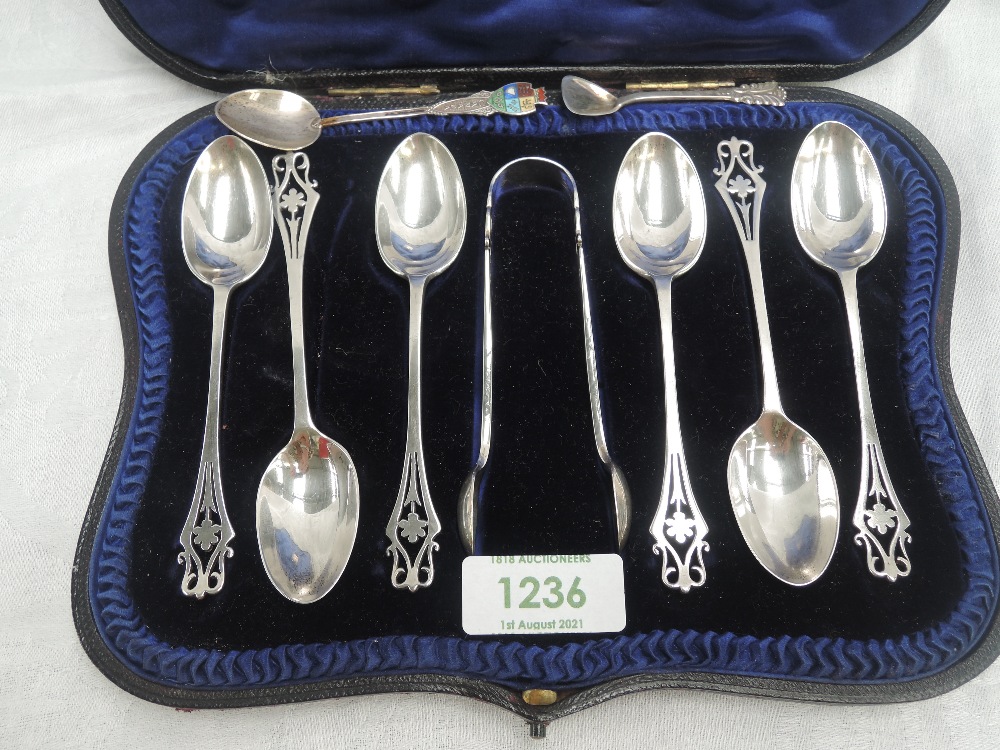 A cased set of six Edwardian silver tea spoons with matching sugar nips having pierced decoration to