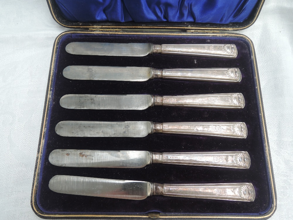 A cased set of six Edwardian silver handled dessert knives having moulded handles with scallop shell