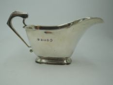 A silver Art Deco style sauce boat of plain form having architectural handle and rectangular foot,