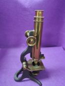 An early 20th century scientific microscope having a brass and cast body with mahogany case made