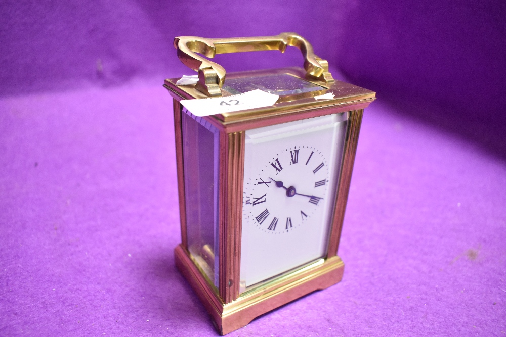 A French brass cased carriage clock having visible escape and bevel edged panels with enamel face