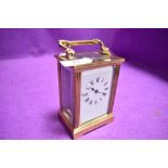 A French brass cased carriage clock having visible escape and bevel edged panels with enamel face