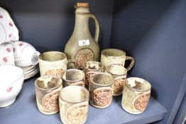 A wine decanter and goblet set by Tremar pottery and two additional mugs