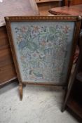 An oak framed embroidered fire screen