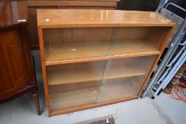 A mid 20th Century golden oak low bookcase, having double glass sliding doors, width approx. 92cm