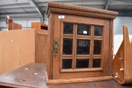 An early 20th Century golden oak wall cabinet, having glazed door