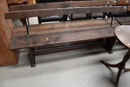 A traditional church pew, of primitive form , with open back and metal rail supports, width