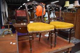 A pair of Victorian mahogany dining chairs havkng overstuffed seats