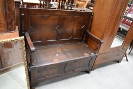 A traditional oak monks bench having cushioned style panels, width approx. 115cm