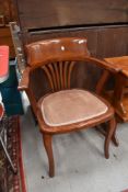 An early 20th Century oak office armchair having later stain and upholstered seat pad