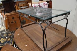 A modern wrought iron frame coffee table having glass top