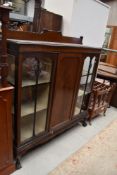 An early 20th Century mahogany display cabinet having ledge back, central cupboard flanked by