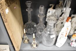 Three antique glass decanters and a pair of Victorian candle sticks.