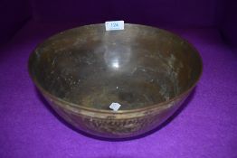 A brass singing bowl having cast Chinese characters to bottom and chased design of dragons and