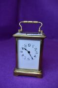 A vintage brass carriage clock having visible escape and enamel face and bevelled glass sides,