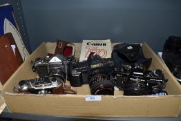 Four cameras including a Canon T70 with instruction book, a Praktica BC1, a Halina 35X and a