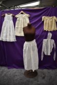 A collection of baby clothing including gowns and apron, all around 1920s.