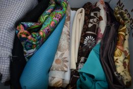 A box full of vintage upholstery and dress fabrics, some large pieces.