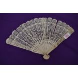 An intricate antique fan having carved ribs and mother of pearl rivet.
