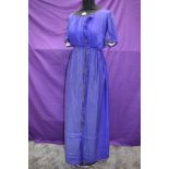 An early 20th century blue silk or silk blend dress having metallic thread edging and glass bead