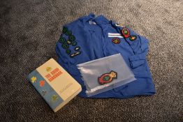 A 1960s girl guides blouse with a collection of badges, book and spare badge.