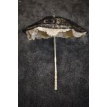 A Victorian parasol having fine black lace over cream tatting and silk ground,white carved handle