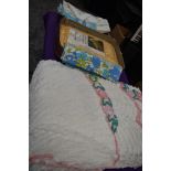 A suitcase containing a vintage candlewick bed throw, an ochre nylon double bed throw in packaging