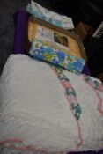 A suitcase containing a vintage candlewick bed throw, an ochre nylon double bed throw in packaging