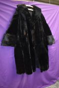 A striking vintage black fur coat having wide sleeve openings with turn up and shawl collar,serviced