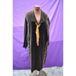 A black velvet 1920s dress having copper thread work and ribbon to neck.