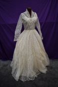 A 1950s wedding dress in box with full embroidered tulle skirt and buttons detail to front.