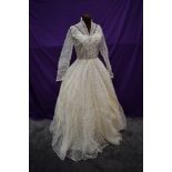 A 1950s wedding dress in box with full embroidered tulle skirt and buttons detail to front.