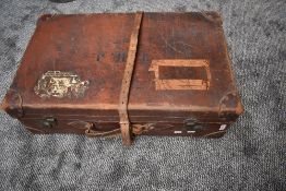 An antique leather suitcase having remnants of labels including LMS.