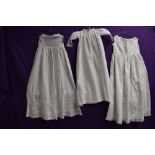 Three Victorian childrens gowns, lace and pin tuck details to hems of some.