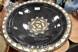 A large terracotta bowl having Islamic design with metal rim and black glaze